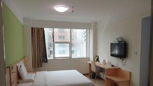 A hotel room with a bed, a desk, a chair, a TV, and a window with a view of buildings. - 7 Days Inn Tangshan Haigang District Haicheng Road (Tangshan)