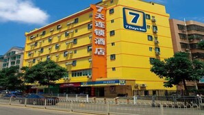 A 7 Days Inn hotel with multiple floors, a prominent orange sign, and a clear blue sky. - 7 Days Inn Tangshan Haigang District Haicheng Road (Tangshan)