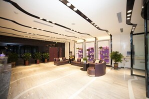 A modern lobby with a curved ceiling, plush seating, potted plants, and a reception desk. - Chaoman Hotels (Tai'an)