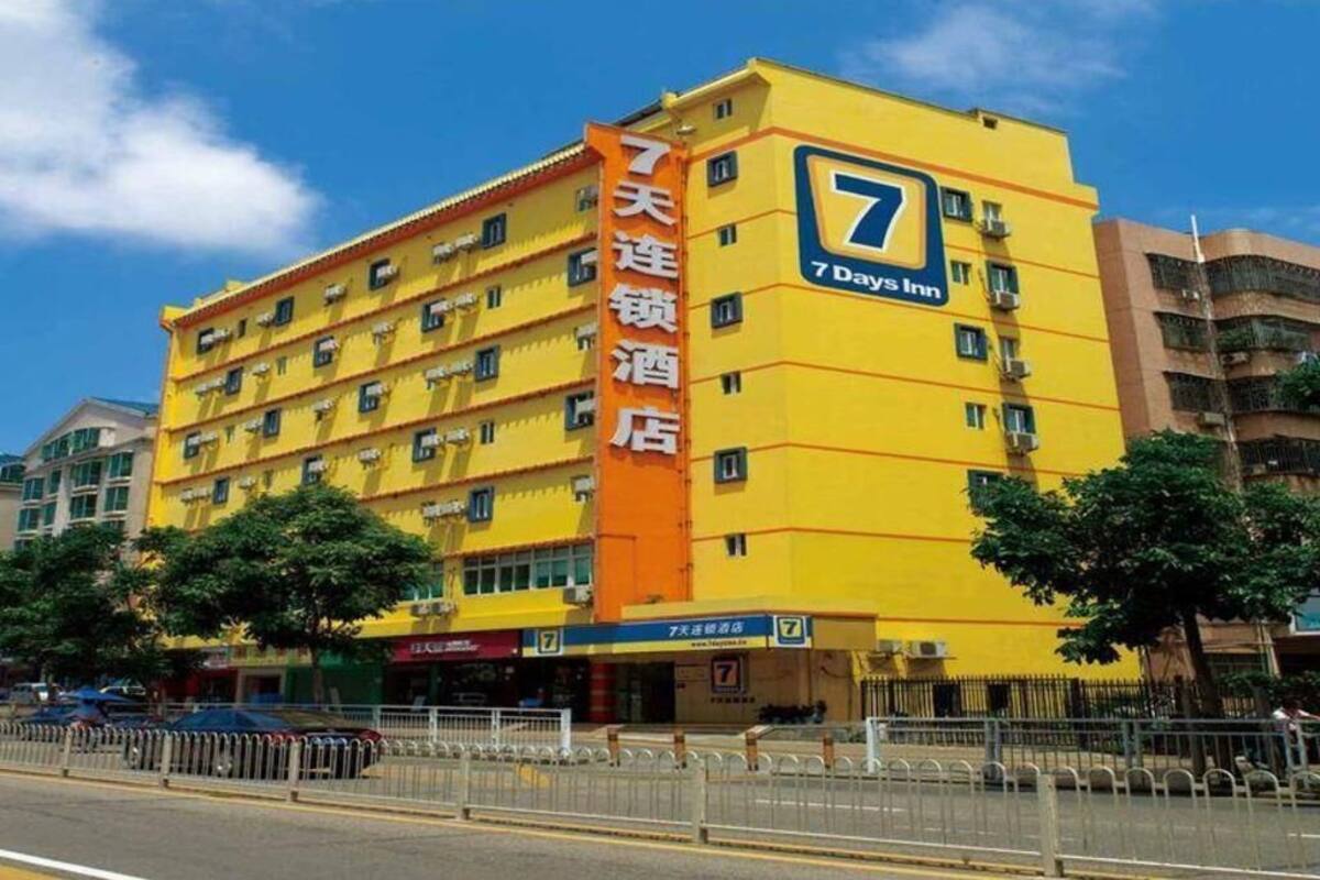 Un hotel 7 Days Inn con fachada amarilla, varios pisos y un letrero naranja llamativo.