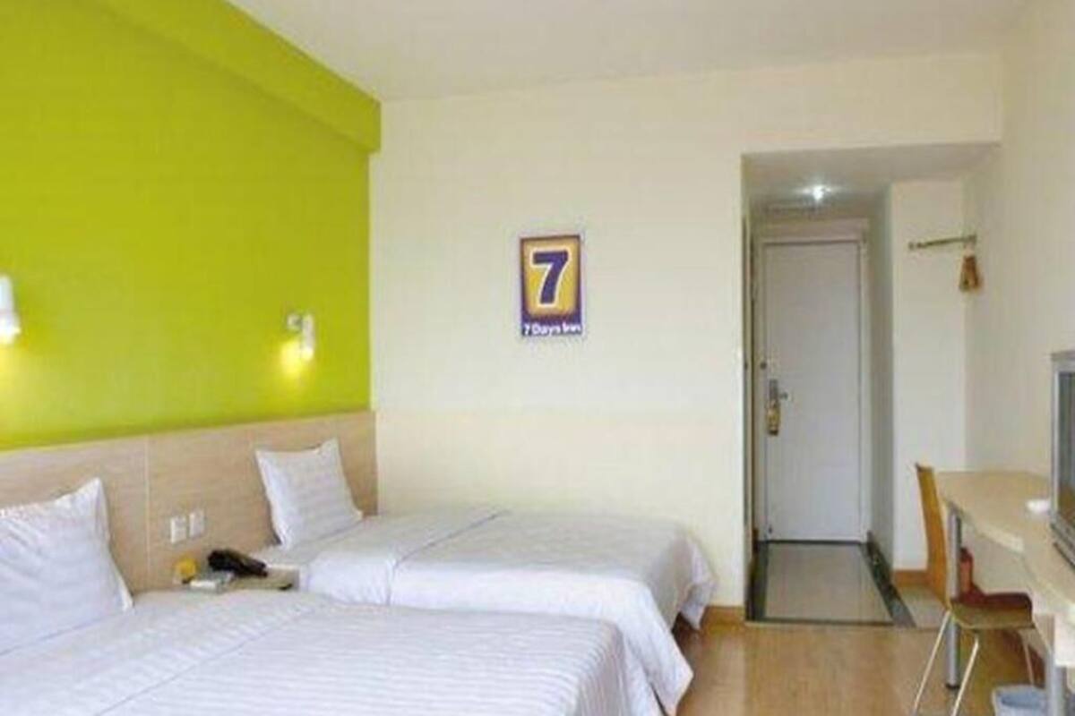 Habitación de hotel con dos camas, un escritorio y una puerta.