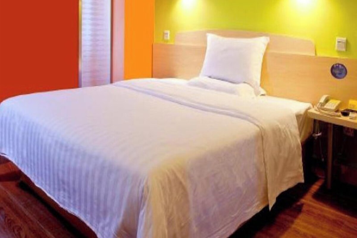 A hotel room with a bed, bedside table, and a wall-mounted telephone.