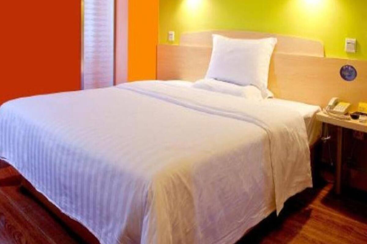 Una habitación de hotel con una cama, una mesita de noche y un teléfono en la pared.