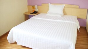 A single bed with a headboard, a bedside table with a phone and a bottle, and a wall with a purple accent. - 7 Days Hotel Mafangshan Subway Station of Wuhan Jiedaokou University of Technology (Wuhan)