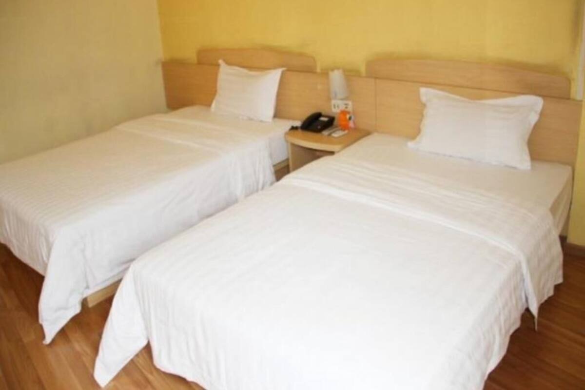 Two single beds with wooden headboards in a room with yellow walls.