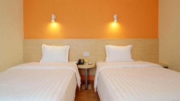 A hotel room with two beds, a small table, and two wall-mounted lights. - 7 Days Hotel Mafangshan Subway Station of Wuhan Jiedaokou University of Technology (Wuhan)