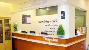 A reception desk with the '7 Days Inn' logo, a website address, and a small potted plant. - 7 Days Hotel Mafangshan Subway Station of Wuhan Jiedaokou University of Technology (Wuhan)