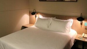 A hotel room with a bed, a nightstand, a lamp, and a wall-mounted picture. - Jinjiang Inn Select (Shenyang)