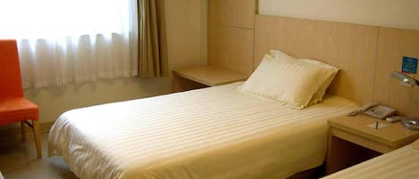 Habitación de hotel con dos camas, una silla, una mesita de noche con un teléfono y un perchero.