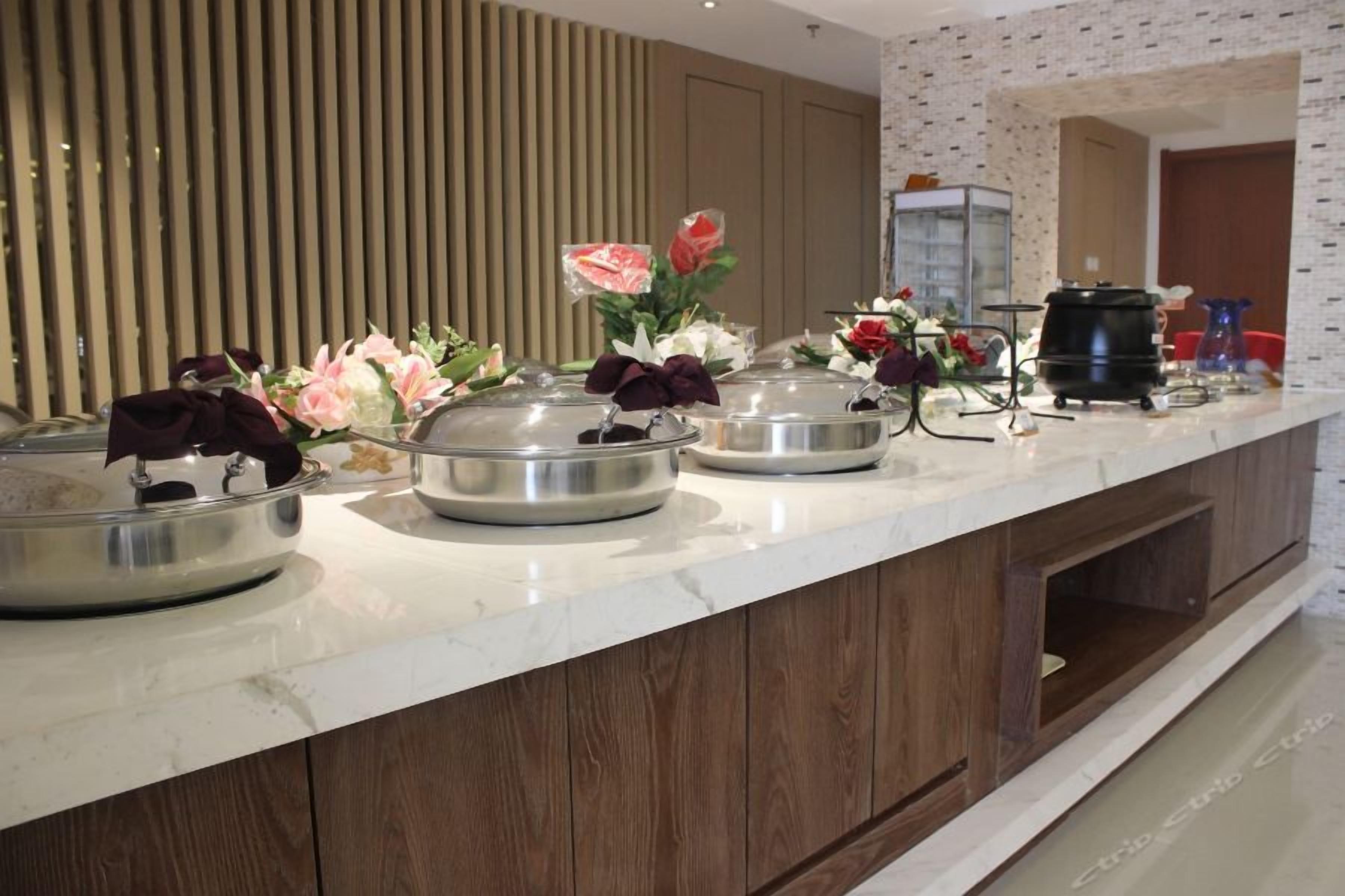 A buffet setup with multiple serving stations, a coffee machine, and decorative flowers.