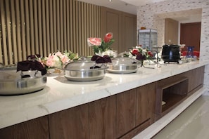 A buffet setup with multiple serving stations, a coffee machine, and decorative flowers. - Jinjiang Inn Select (Shenyang)