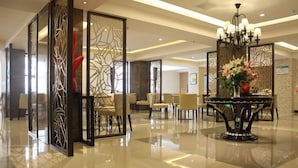 Et hotellobby med et moderne design, med en receptionsdisk, siddeområde og et dekorativt bord med blomster.