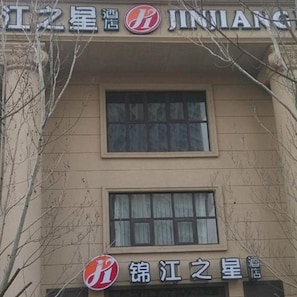 A hotel with a sign that includes Chinese characters and a logo with a red circle and white design. - Jinjiang Inn Select (Shenyang)