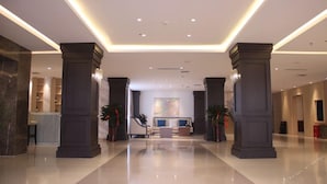 En rummelig lobby med reception, siddepladser og et stort maleri på væggen.