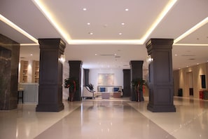 Un vestíbulo amplio con una mesa de recepción, zona de estar y un cuadro grande en la pared.