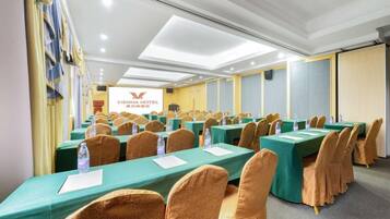 A conference room with multiple tables, chairs, and a presentation screen.