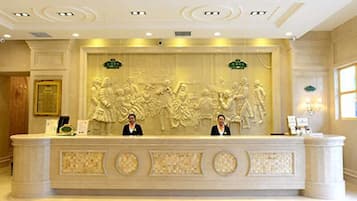 Una recepción con un detallado relieve escultórico, dos recepcionistas y un certificado enmarcado en la pared.