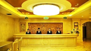 A reception desk with a large, ornate wall mural, a chandelier, and a polished floor. - Vienna International Hotel (Lhasa)