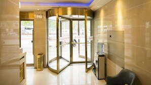 A revolving door with a glass enclosure, a water dispenser, and a chandelier. - Shell Hotel (Dingxi)