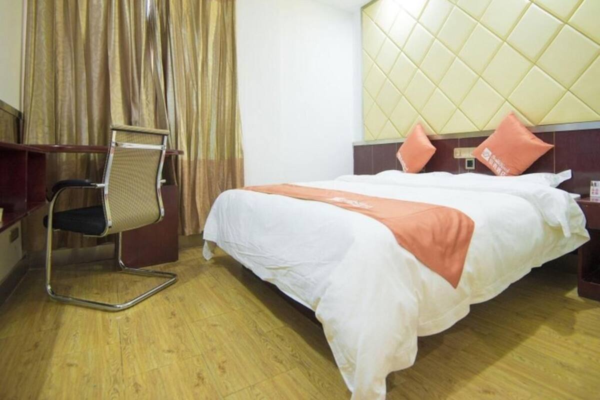 A hotel room with a bed, a desk, and a chair.