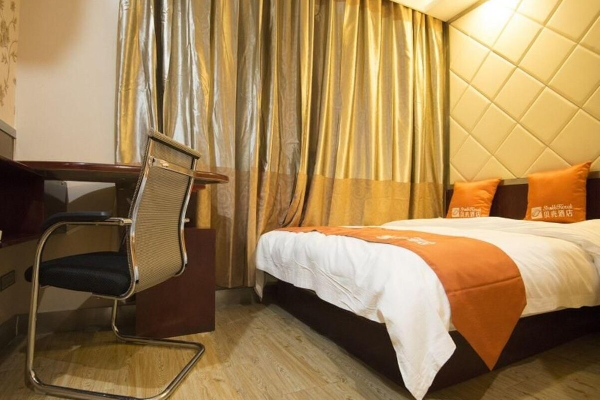 Una habitación de hotel con cama, escritorio y silla.