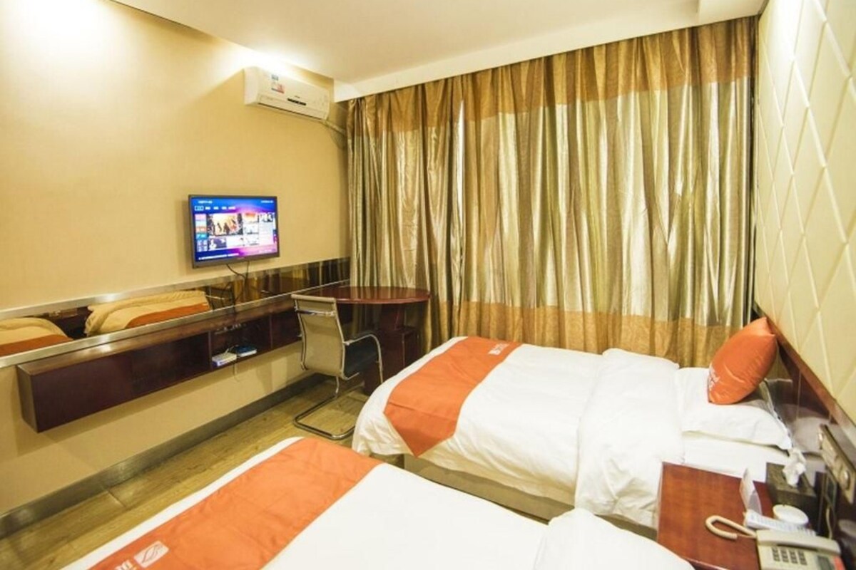 Una habitación de hotel con dos camas, televisión, escritorio y una silla.