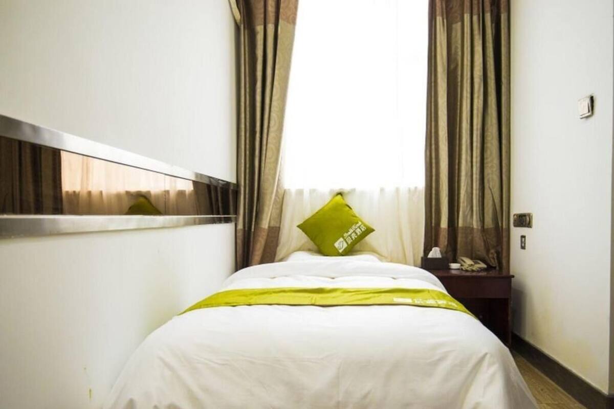 A hotel room with a bed, curtains, a nightstand, and a telephone.