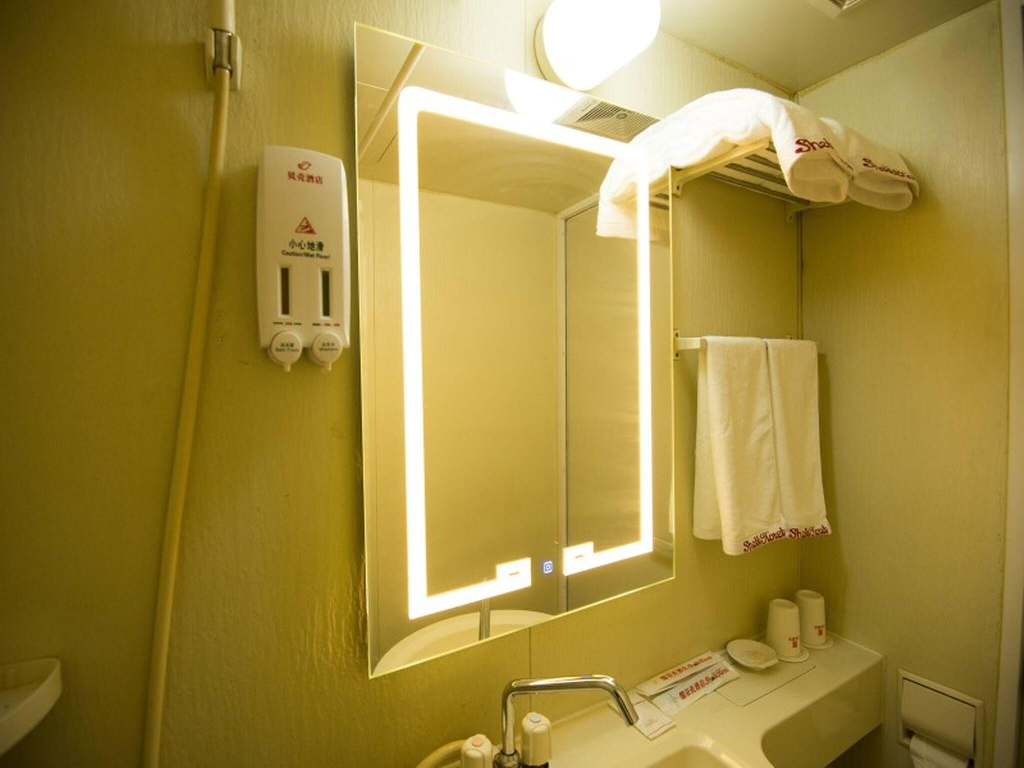 A bathroom with a mirror, sink, towel rack, and a hand dryer.