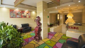 A hotel lobby with a colorful geometric carpet, a decorative horse statue, a chandelier, and a reception desk with signage. - Shell Hotel (Dingxi)