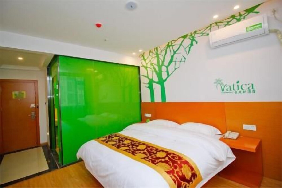 Habitación de hotel con cama, puerta verde, unidad de aire acondicionado y un letrero en la pared.