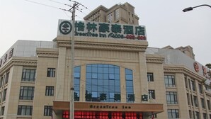 A hotel with a large glass facade, signage for 'GreenTree Inn,' and a prominent entrance. - Greentree (Fuyang)