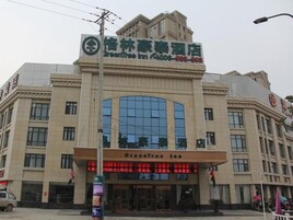 A hotel with a large glass facade, signage for 'GreenTree Inn,' and a prominent entrance.
