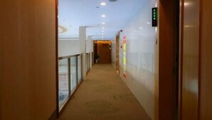 A hotel corridor with a carpeted floor, glass railings, and a digital elevator display. - Greentree (Fuyang)