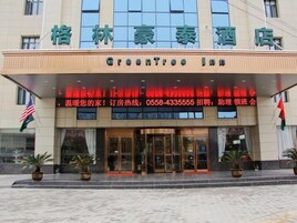 Entrada de un hotel con un cartel que dice 'GreenTree Inn' y un número de contacto para consultas.