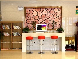 A reception area with a wooden bookshelf, a computer monitor, and three red bar stools.