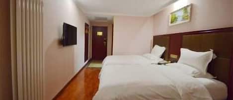 A hotel room with a wooden floor, a bed with white bedding, a flat-screen TV mounted on the wall, and a painting on the wall.