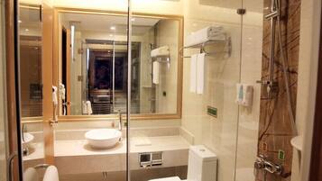 Un baño moderno con cabina de ducha de vidrio, un espejo grande y un inodoro blanco.