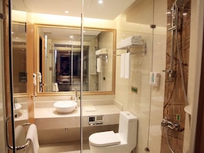 Un baño moderno con cabina de ducha de vidrio, un espejo grande y un inodoro blanco.