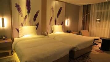 A hotel room with two beds, a sitting area, and a large window with curtains.