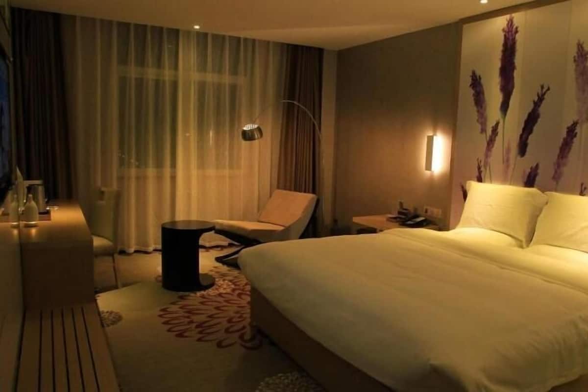 Hotellihuone, jossa on sänky, tuoli, työpöytä ja yöpöytä.