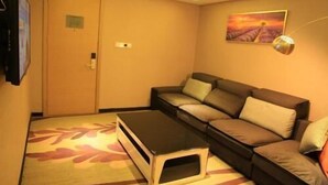 A living room with a sofa, a small table, a door, and a painting on the wall. - Lavande Hotels·tianshui Gangu Yicheng Square (Tianshui)