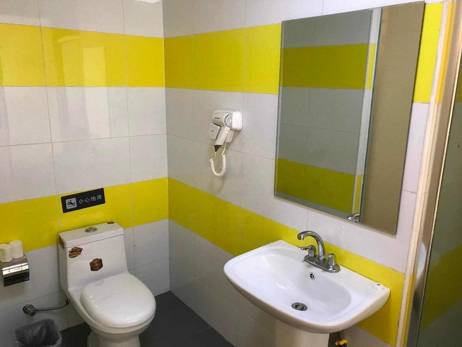 A small bathroom with a toilet, sink, and a hairdryer on the wall.