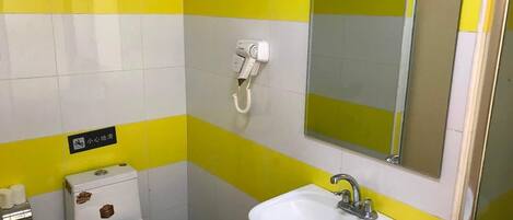 A small bathroom with a toilet, sink, and a hairdryer on the wall.