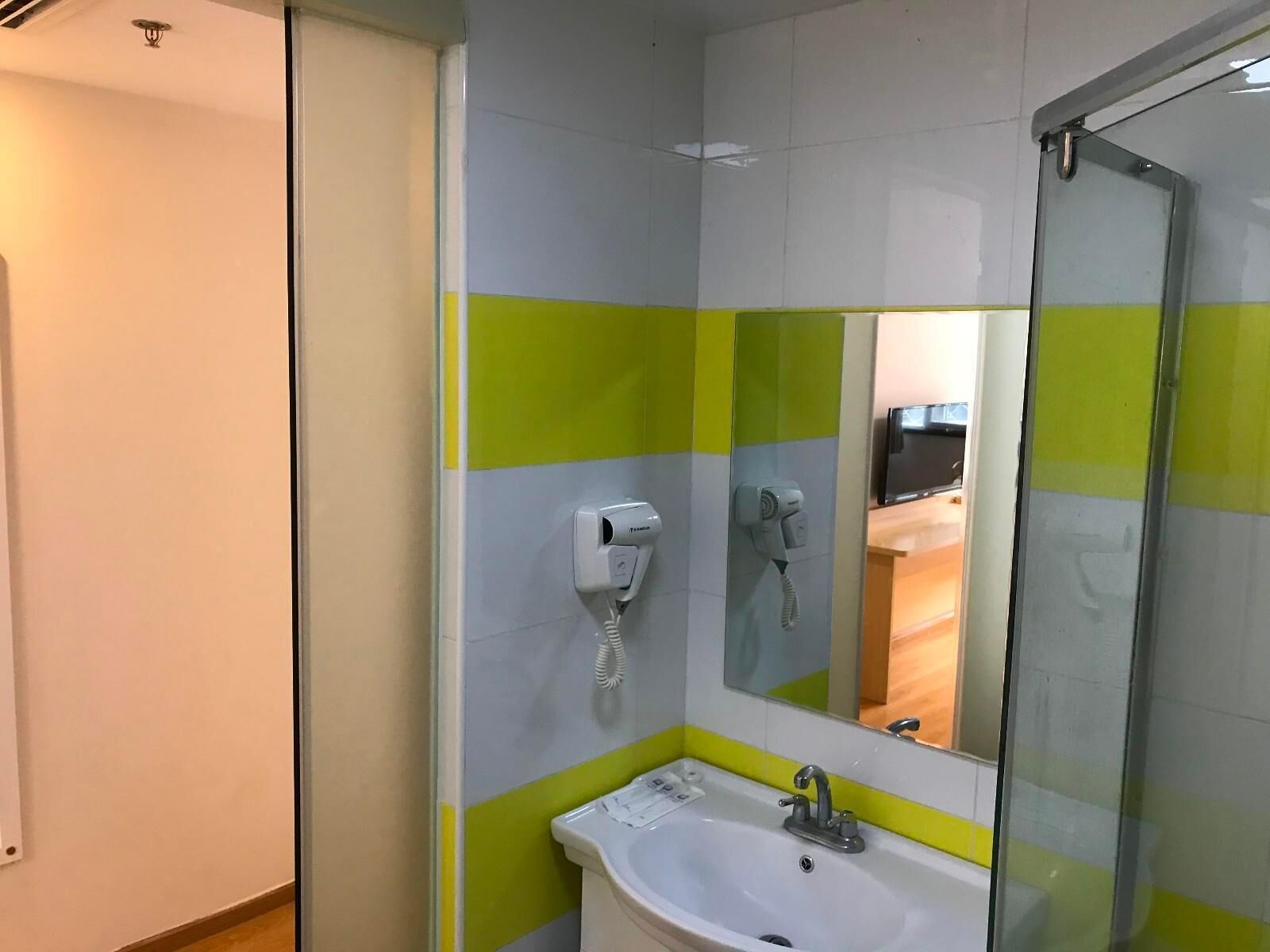 Un bagno con lavandino, specchio e due asciugacapelli montati a parete.