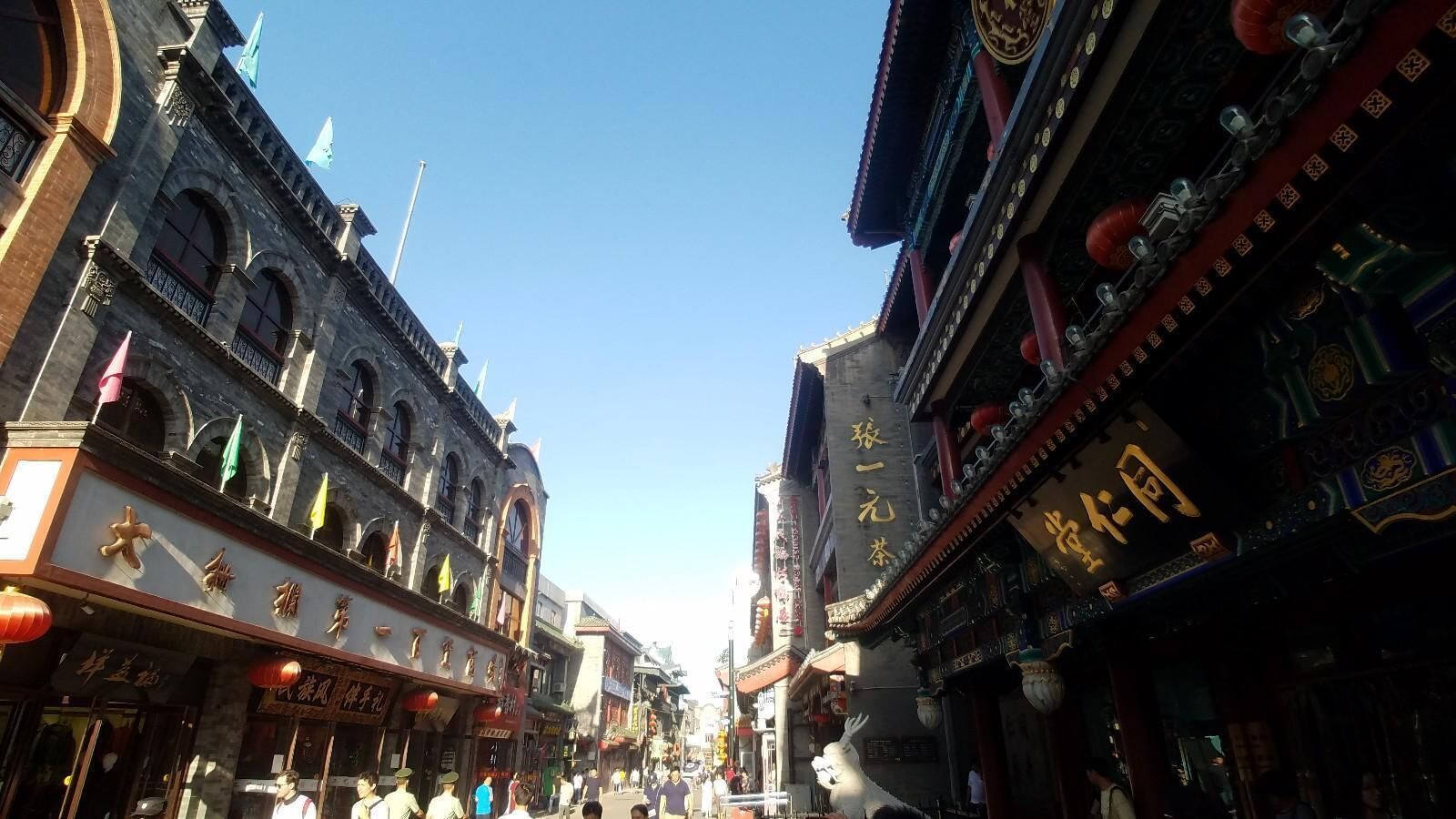Une rue aux bâtiments d’architecture traditionnelle, avec des façades richement décorées et des enseignes écrites dans un alphabet étranger.