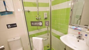 Uma casa de banho com sanita, cabine de duche com cortina de vidro e toalha pendurada, e lavatório com espelho.