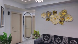 Un couloir avec un mur recouvert de miroirs, une porte, une caméra de surveillance fixée au mur et un élément décoratif mural.
