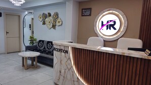 Un espace d’accueil comprenant un comptoir en marbre, un canapé, une petite table et des œuvres d’art décoratives murales.