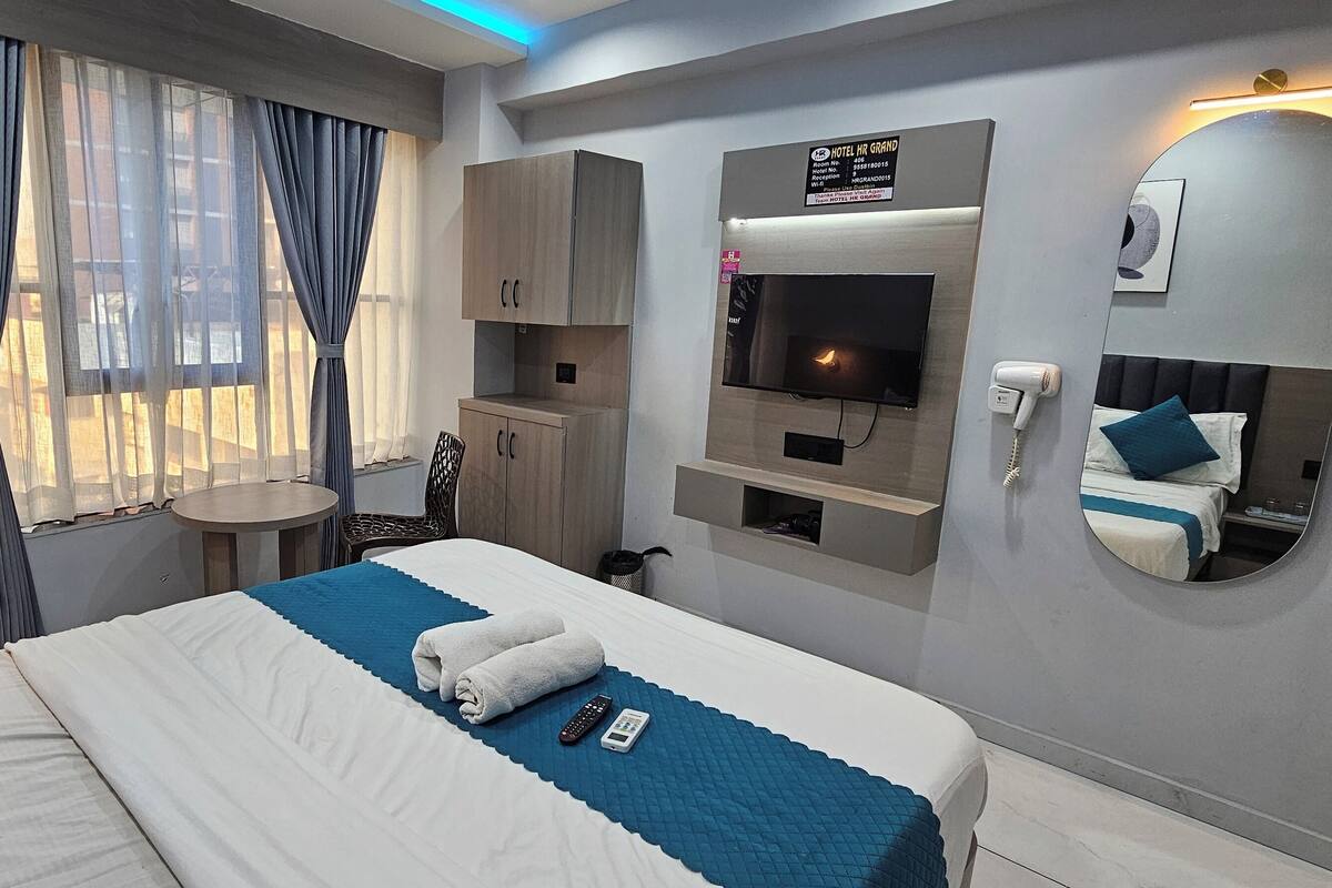 Een hotelkamer met een bed, een bureau, een televisie, een spiegel en een bord met de naam van het hotel.