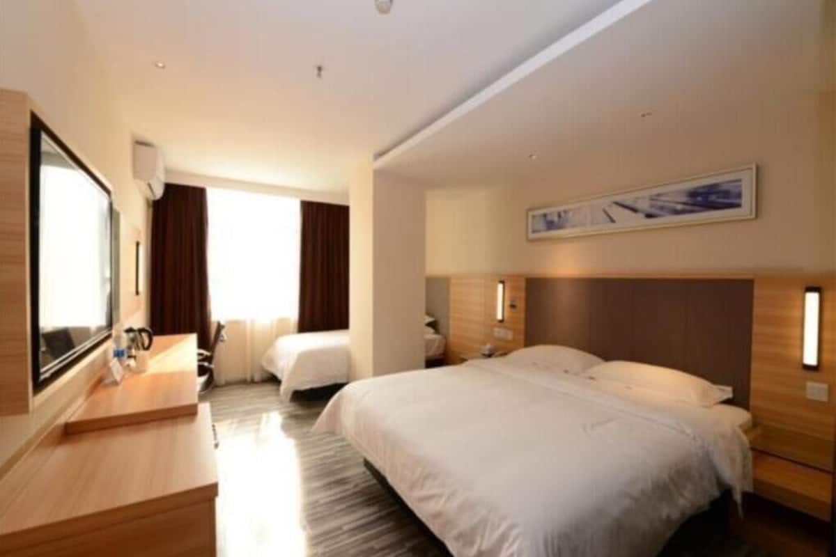 Habitación de hotel con una cama grande, un escritorio, una silla y un televisor.
